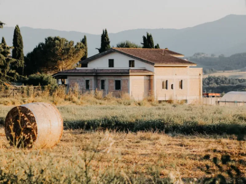 Casale di campagna con balle di fieno e colline sullo sfondo